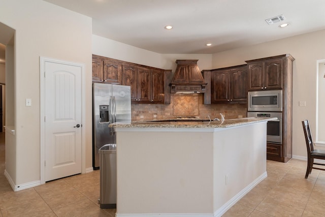 kitchen featuring stainless steel appliances, backsplash, a kitchen island with sink, dark brown cabinets, and custom exhaust hood