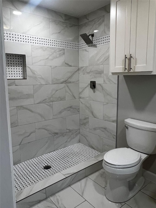 bathroom featuring toilet and a tile shower