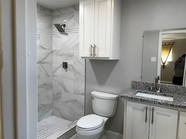 bathroom with tiled shower, vanity, and toilet