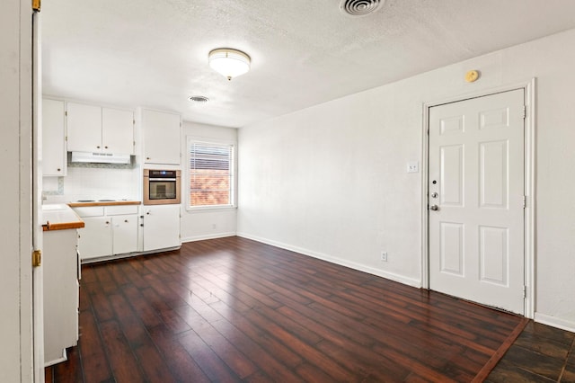 kitchen with stainless steel oven, dark wood-type flooring, a textured ceiling, decorative backsplash, and white cabinets