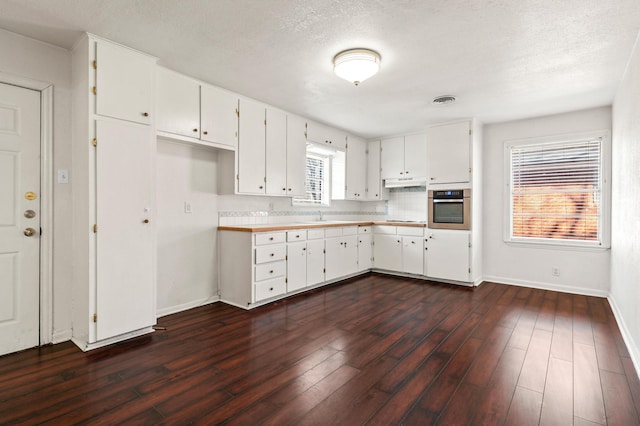 kitchen featuring decorative backsplash, white cabinetry, oven, and dark hardwood / wood-style floors