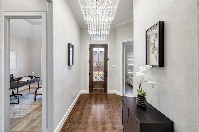 entrance foyer with a chandelier, wood-type flooring, and ornamental molding