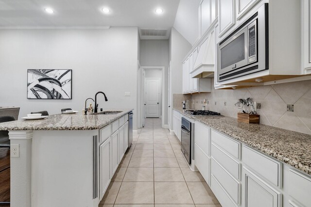 kitchen with light stone counters, sink, white cabinets, and stainless steel appliances