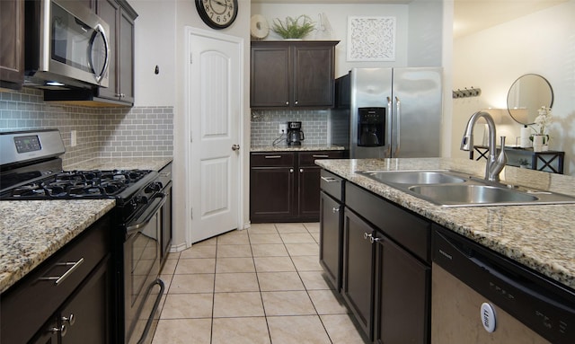 kitchen with sink, light tile patterned floors, light stone counters, stainless steel appliances, and dark brown cabinets