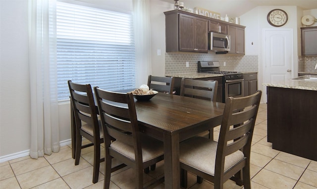 tiled dining room with vaulted ceiling and sink