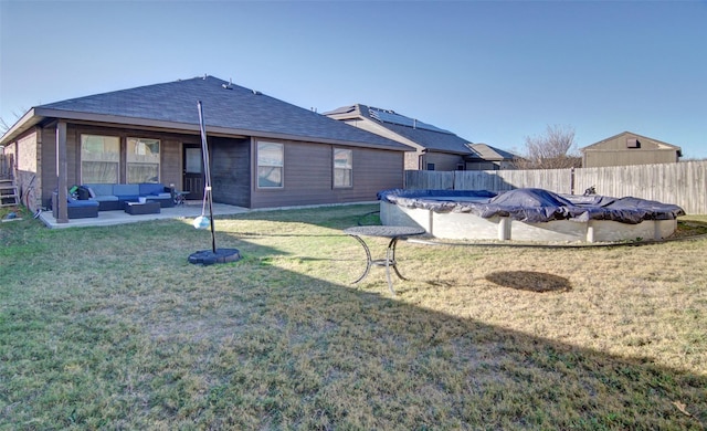 rear view of property featuring an outdoor living space, a covered pool, and a lawn