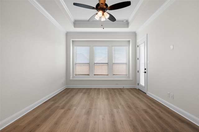 empty room with crown molding, a tray ceiling, ceiling fan, and light wood-type flooring