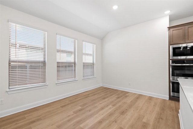 unfurnished dining area with lofted ceiling and light hardwood / wood-style floors