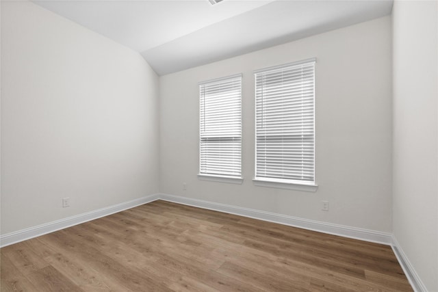 unfurnished room with hardwood / wood-style flooring and vaulted ceiling