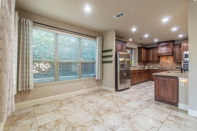 kitchen with visible vents, custom range hood, backsplash, appliances with stainless steel finishes, and light stone countertops