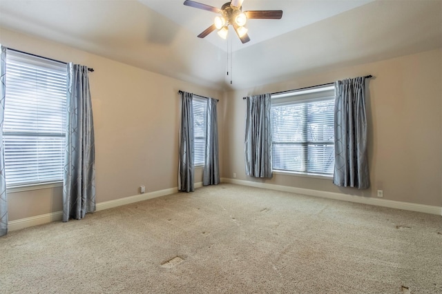 carpeted empty room with a ceiling fan, vaulted ceiling, and baseboards