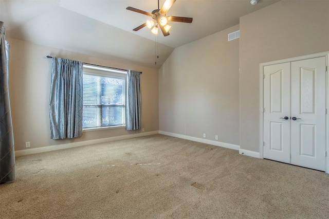 carpeted empty room with lofted ceiling, ceiling fan, and baseboards