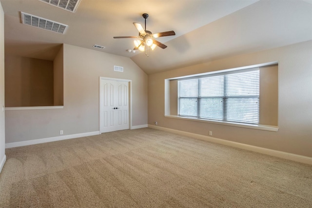 carpeted spare room featuring visible vents, vaulted ceiling, and baseboards