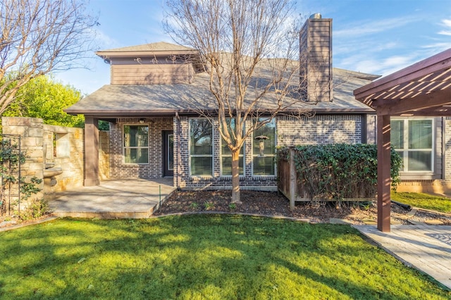 rear view of property with a patio area, brick siding, a yard, and a chimney