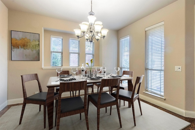 dining room with a chandelier, baseboards, and wood finished floors