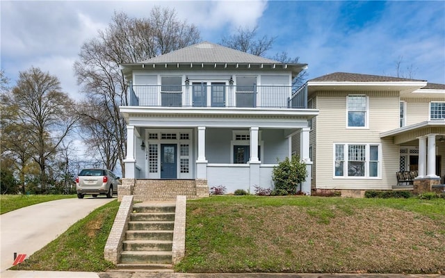 view of front of house with a balcony, a front lawn, and covered porch