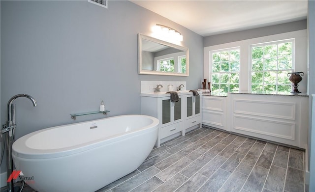 bathroom featuring wood-type flooring, vanity, and a tub to relax in