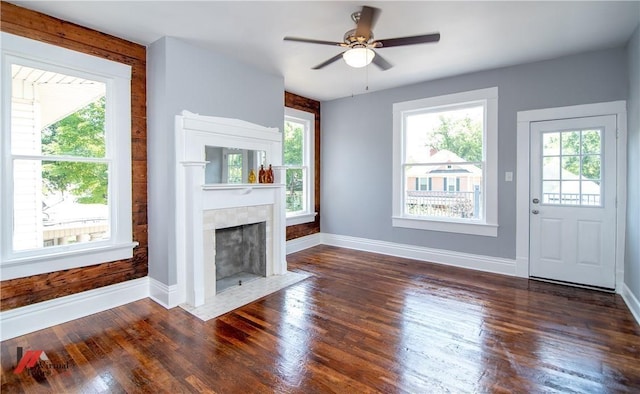 unfurnished living room featuring ceiling fan, dark hardwood / wood-style floors, and a tiled fireplace