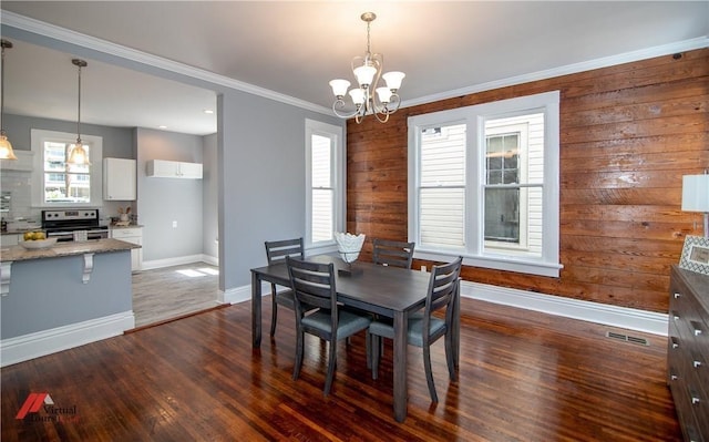 dining area featuring dark hardwood / wood-style flooring, a chandelier, and ornamental molding