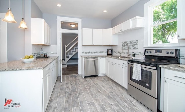 kitchen featuring white cabinetry, sink, hanging light fixtures, and appliances with stainless steel finishes