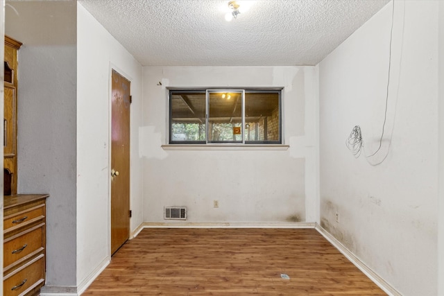 empty room with wood-type flooring and a textured ceiling