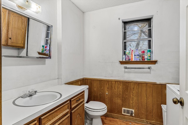 bathroom featuring hardwood / wood-style floors, vanity, a textured ceiling, washer / clothes dryer, and toilet