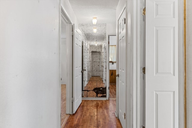 hall with wood-type flooring and a textured ceiling