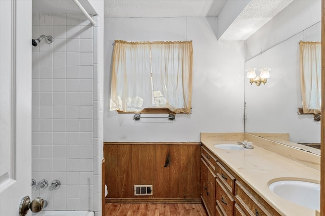 bathroom with hardwood / wood-style flooring, vanity, a textured ceiling, and wooden walls