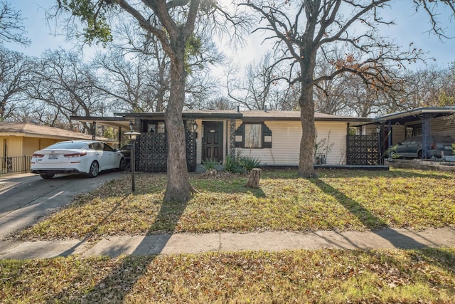 ranch-style house featuring a carport and a front lawn