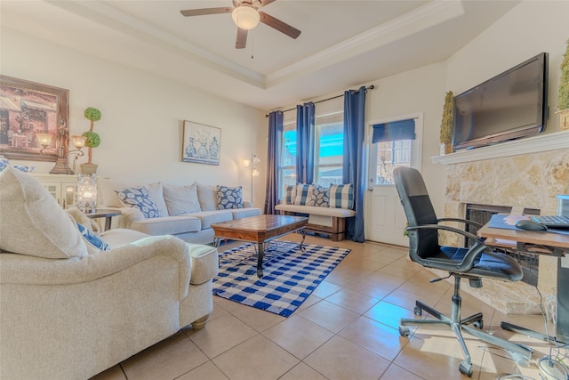 tiled living room with ceiling fan, crown molding, a fireplace, and a tray ceiling