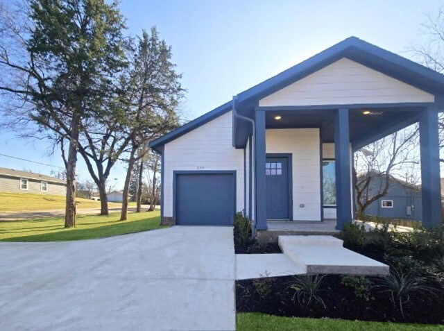 view of front facade featuring a porch, a garage, and a front yard