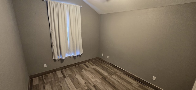 unfurnished room with hardwood / wood-style flooring and vaulted ceiling