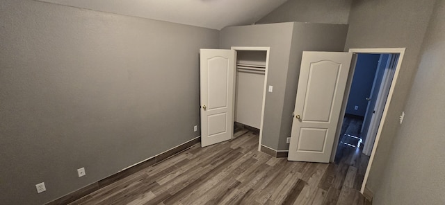 unfurnished bedroom featuring a closet, dark wood-type flooring, and vaulted ceiling