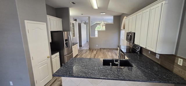 kitchen featuring sink, a chandelier, dark stone countertops, appliances with stainless steel finishes, and white cabinets