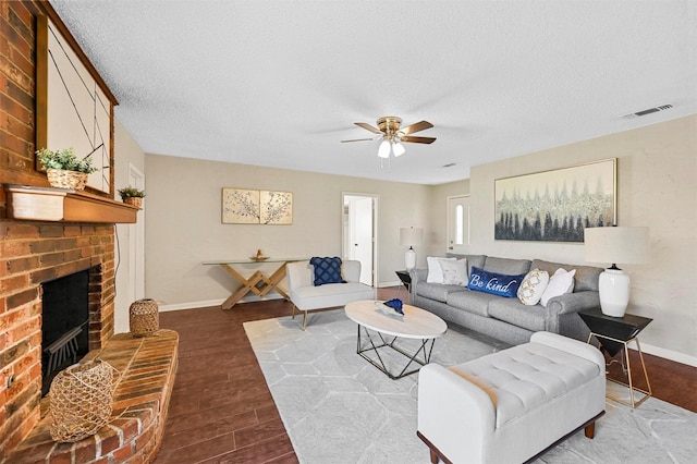 living room with a textured ceiling, a brick fireplace, hardwood / wood-style floors, and ceiling fan