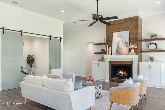 living room with a barn door, ceiling fan, dark hardwood / wood-style floors, and ornamental molding