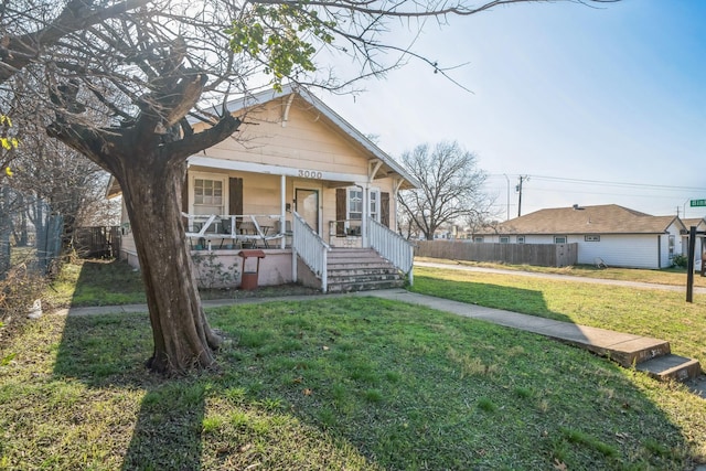 bungalow featuring covered porch and a front yard