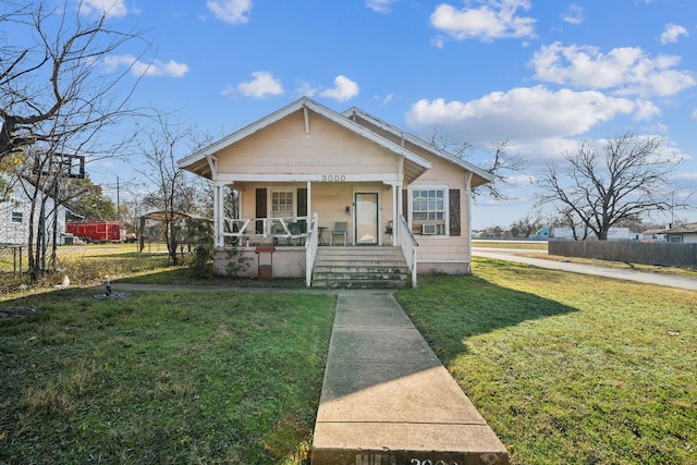 bungalow-style home featuring covered porch and a front lawn