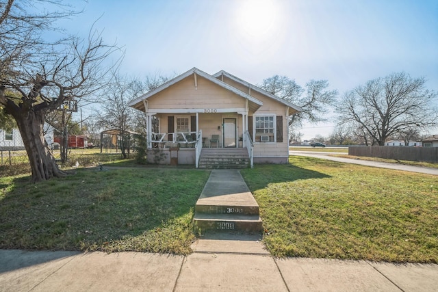 bungalow-style home featuring covered porch and a front yard