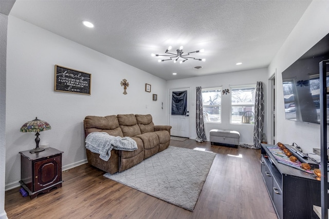 living room featuring dark wood-type flooring, a chandelier, and a textured ceiling