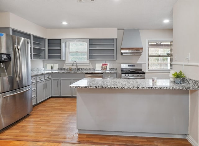 kitchen with custom exhaust hood, a healthy amount of sunlight, light stone counters, and appliances with stainless steel finishes