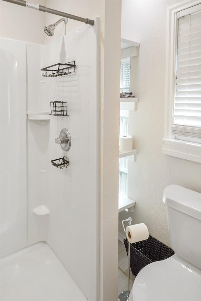 bathroom featuring a shower, toilet, and a healthy amount of sunlight