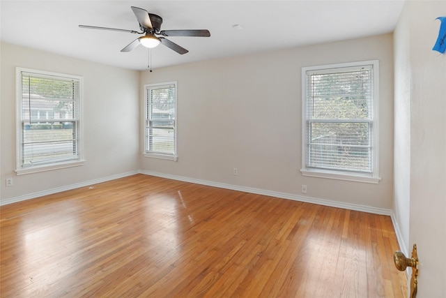 empty room with ceiling fan, a wealth of natural light, and light wood-type flooring