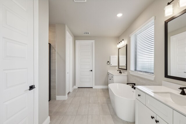 bathroom with a bath, vanity, and tile patterned floors