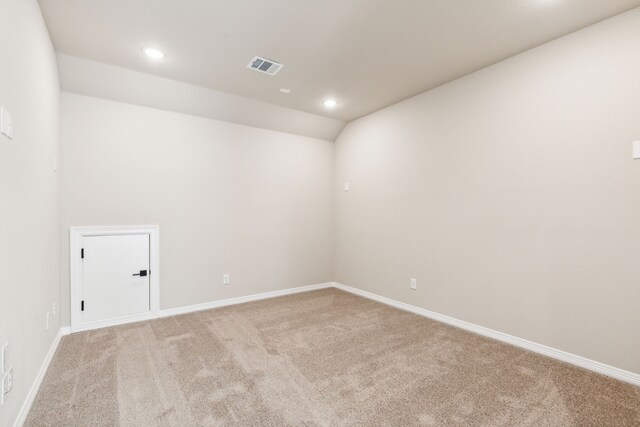 empty room featuring light colored carpet and lofted ceiling