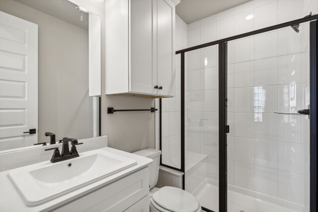 bathroom with vanity, toilet, and a shower with shower door