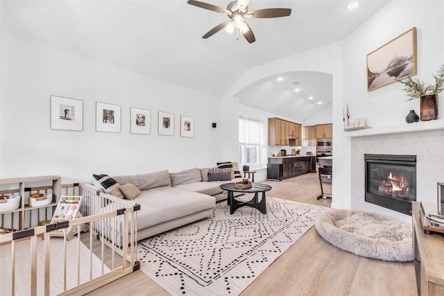 living room featuring ceiling fan, lofted ceiling, a high end fireplace, and light hardwood / wood-style floors