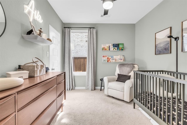 bedroom with light carpet, a nursery area, and ceiling fan