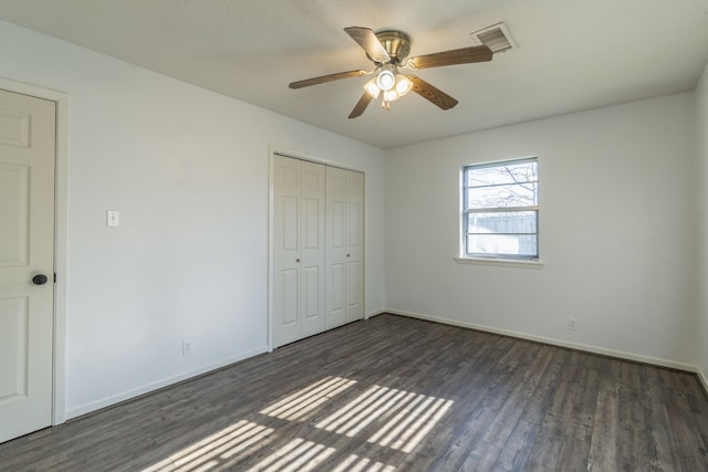 unfurnished bedroom with ceiling fan, dark hardwood / wood-style floors, and a closet