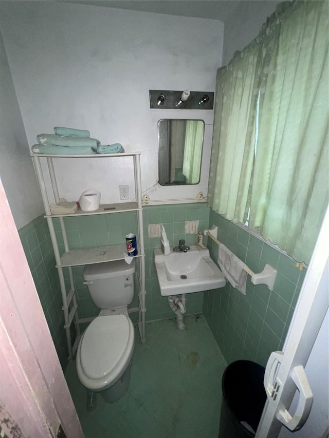 bathroom with tile patterned flooring, toilet, sink, and tile walls